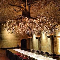 a long table is set with wine glasses and place settings under a chandelier