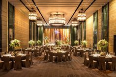 a banquet hall with round tables and chandeliers on either side of the room