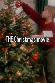 a young boy is decorating a christmas tree with the words, the christmas movie