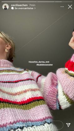 a woman flying a kite in the air while wearing a pink and green striped sweater