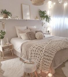 a white bed topped with lots of pillows and blankets next to a night stand filled with candles