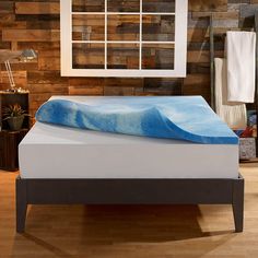 a bed with a blue sheet on it in a room that has wood walls and wooden flooring