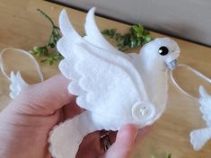 a hand holding a white bird made out of felt