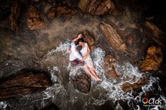 two people are sitting on rocks in the water and one person is holding his head