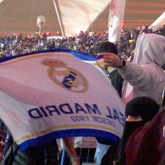 a group of people standing next to each other in front of a crowd holding a flag