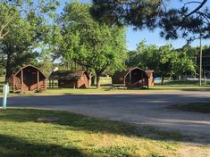 there are several small wooden buildings in the park with trees around them and grass on the ground