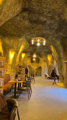 the inside of a restaurant with tables and chairs in an underground passage that is lit up by lights