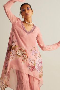 Blush pink tunic with vintage floral print, highlighted with stone embellishments. Paired with a coordinating floral print gharara.
Components: 2
Pattern: Print
Type Of Work: Floral
Neckline: V Neck
Sleeve Type: Full Sleeves
Fabric: Viscose Chinon
Color: Pink
Other Details: 
Model height:  5 ft 9 inches, wearing size S
Length:
Tunic Front Length - 30 inches
Tunic Back Length - 43 inches
Pant Length - 42 inches
Asymmetric hemline tunic
Occasion: Sangeet - Aza Fashions Bohemian Floral Print Salwar Kameez For Wedding, Traditional Drape Sharara With Floral Print For Eid, Unstitched Wedding Kurta Tunic, Bohemian Palazzo Set With Straight Kurta For Wedding, Bohemian Sharara For Wedding And Transitional Seasons, Bohemian Palazzo Set For Wedding, Bohemian Wedding Sharara, Bohemian Long Sleeve Wedding Sets, Bohemian Palazzo Set With Sheer Dupatta For Eid