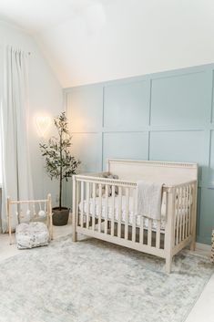 a baby's room with a white crib and blue paneled wall behind it