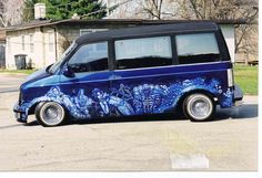 a blue van parked in front of a house with graffiti on it's side