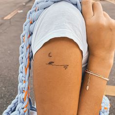 a woman with a tattoo on her left arm holding onto a blue knitted bag