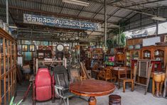 a room filled with lots of wooden furniture and antiques on display in front of a sign