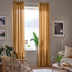 a living room filled with furniture and a large window covered in yellow drapes