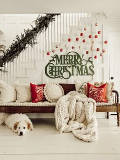 a dog laying on the floor next to a couch with christmas decorations hanging above it