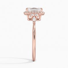 a rose gold ring with an oval cut diamond on the center and side stones in the middle