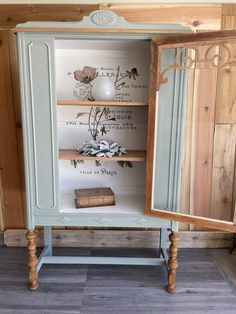 an old cabinet is painted blue and has flowers on the top shelf, with a mirror above it