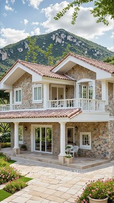 a stone house with white windows and balconies on the second floor is surrounded by greenery