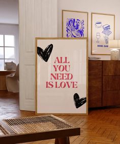 an all you need is love poster hangs on the wall next to a wooden table