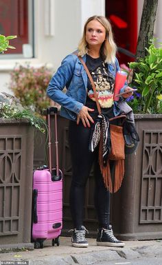 a woman standing next to a pink suitcase