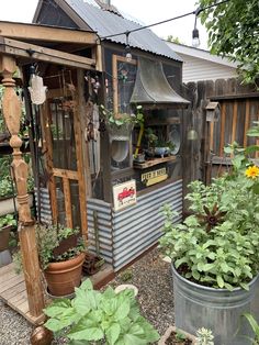 an outdoor garden shed with potted plants and hanging pots on the outside wall,