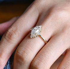 a close up of a person's hand with a diamond ring on their finger