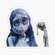 a woman with blue hair and makeup is holding a sticker in her right hand