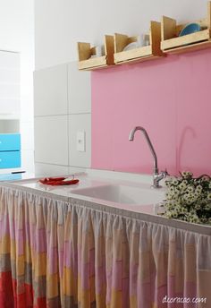 a kitchen with pink walls and colorful curtains