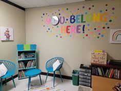 a room with chairs, bookshelves and a sign that says you belong here