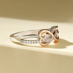 Embrace the intertwining beauty of love and elegance with our sterling silver ring. The open heart and twisted knot design symbolize a bond that is strong, yet tender. The rose gold heart adds a touch of warmth and romance to this exquisite piece. Let this ring grace your hand as a reminder of the intertwining paths of love and connection. The intricate design speaks to the complexity and beauty of relationships, while the heart symbolizes the depth of emotion and affection shared between souls. Wear this sterling silver ring as a symbol of enduring love and unity, a testament to the intertwining of hearts and the strength found in togetherness.Carat Weight: 0.3 ctStone Size: 1 mmStone Type: Jeulia® StoneNumber of Stones: 30 Stone Color: Diamond WhiteStone Shape: RoundWeight: 3.1 gWidth: 1 Infinity Knot, Infinity Design, Infinity Heart, Knot Design, Rose Gold Heart, Open Heart, Gold Heart, Intricate Design, The Rose