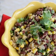 a yellow bowl filled with beans and couscous on top of a red napkin