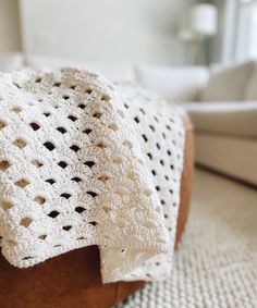 a white crocheted blanket sitting on top of a brown chair