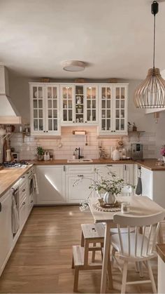 a kitchen filled with lots of white cabinets and counter top space next to a dining room table