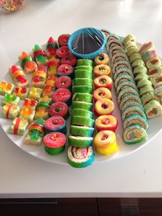 a white plate topped with lots of different colored donuts and pastries on top of each other