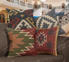 three decorative pillows sitting on top of a couch in front of a spiral stair case