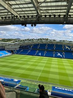 an empty soccer stadium with blue seats and sky in the backgrouds as people watch