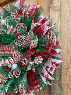 a christmas wreath with red, white and green decorations on top of a wooden table