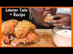 lobster tails and crawfish on a wooden cutting board with a woman eating them