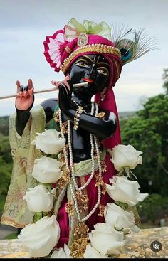 a statue is dressed in black and white with flowers on the ground next to it