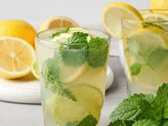 two glasses filled with lemonade and mint garnish next to sliced lemons