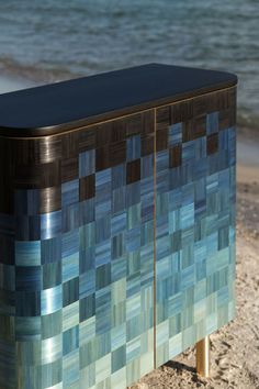 a blue and brown cabinet sitting on top of a sandy beach next to the ocean