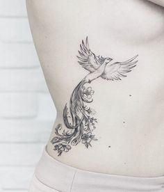 a woman's stomach with a bird tattoo on her lower back, and flowers around the waist