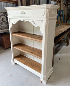 an antique white bookcase with wooden shelves