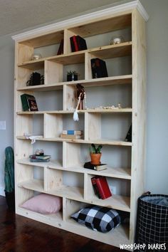 a bookshelf made out of plywood and wood with cushions on the floor