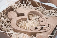 a wooden mickey mouse cutout in a box filled with shredded up hay and straw