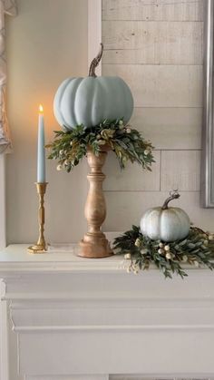 a white mantle with candles and pumpkins on it