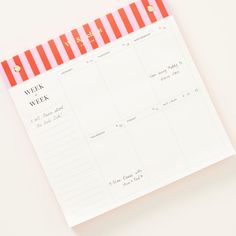 a pink and red striped planner on top of a white table