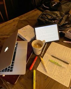 an open laptop computer sitting on top of a wooden table next to a cup of coffee