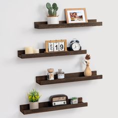 two wooden shelves with pictures, photos and other items on them against a white wall