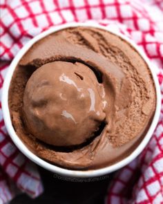 a bowl filled with chocolate ice cream on top of a red and white checkered cloth