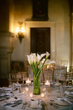 a table set with candles and flowers in a vase on it's centerpiece